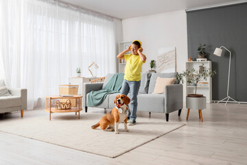 Little African-American boy and cute beagle dog with headphones listening to music at home