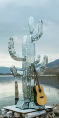 Silver disco cactus with a guitar by the lake.Minimal creative party concept.
