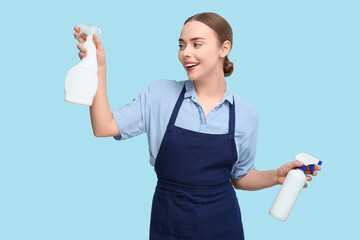Young woman with spray bottles on blue background