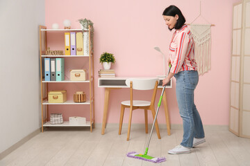 Pretty young woman mopping floor at home