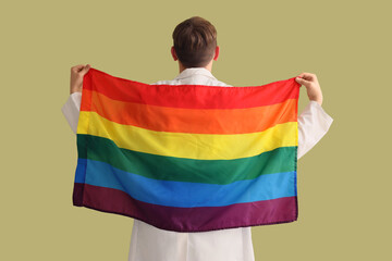 Male dentist with LGBT flag on green background, back view
