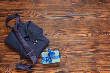 Shirt, tie and gift box on brown wooden background. Father's day celebration. Top view