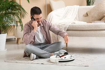 Young man calling tech support for fixing robot vacuum cleaner at home