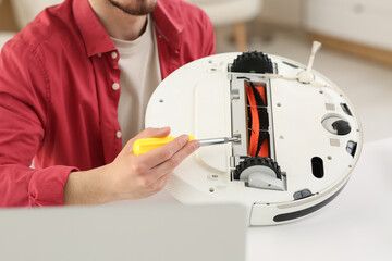 Male blogger recording robot vacuum cleaner fixing tutorial at home
