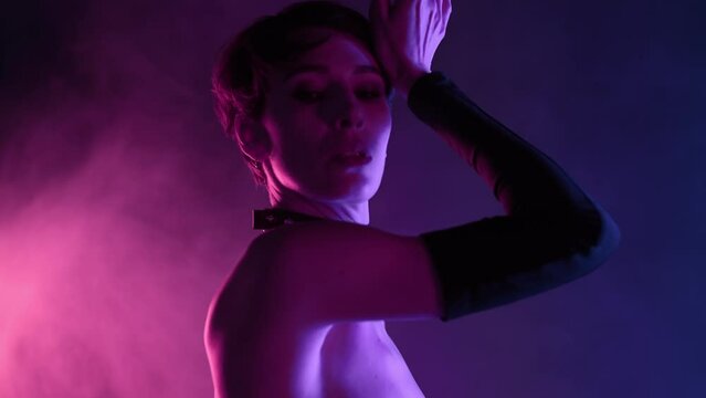 Dominatrix woman in sexy corset dancing in colorful pink light. Mistress, fetish