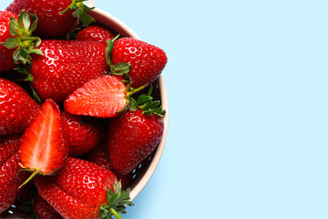 Colander with sweet fresh strawberries on blue background