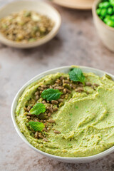Hummus made of chickpeas, fresh green peas and mint, sprinkled with seeds