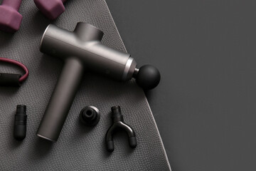 Percussive massager and sports equipment on dark background