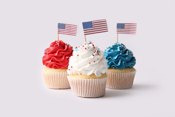 Tasty patriotic cupcakes with USA flags on grey background. American Independence Day