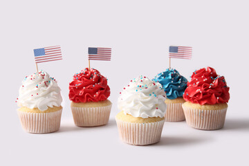 Tasty patriotic cupcakes with USA flags on grey background. American Independence Day