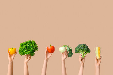 Female hands holding fresh vegetables on beige background
