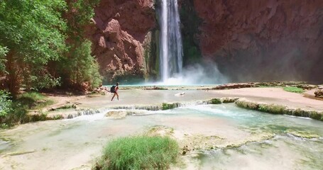 Cinematic drone shot flying over beautiful stream towards desert waterfall