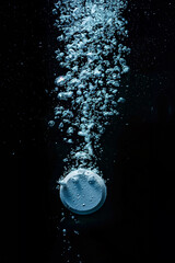 Effervescent pill with fizzy bubbles in water. Soluble tablet dissolving falling in sparkling water with fizzy bubbles