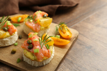 Tasty canapes with salmon served on wooden table, closeup. Space for text