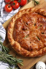 Tasty homemade pie, rosemary and tomatoes on wooden table, flat lay