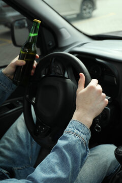 Man with bottle of beer driving car, closeup. Don't drink and drive concept