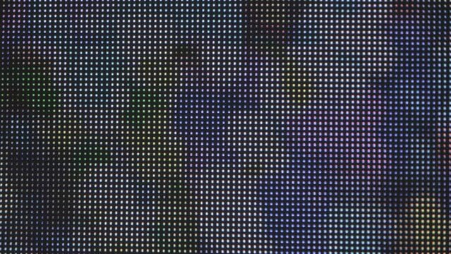 Extreme close-up shot: an LED grid display, featuring large illuminated dots that change color in an animated sequence. Slow movement.