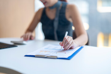 A woman is writing on a piece of paper with a pen