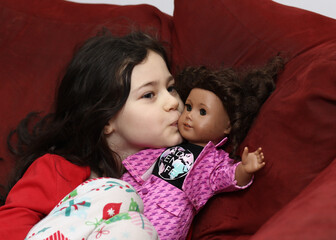 beautiful young girl  playing with a doll on the couch