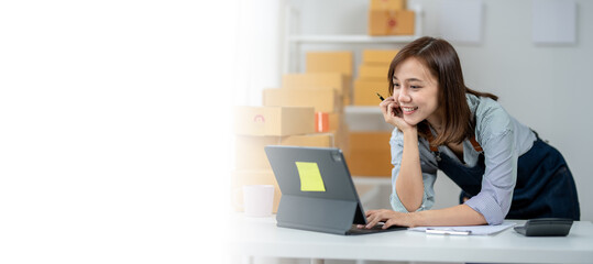 A woman is sitting at a desk with a laptop and a tablet