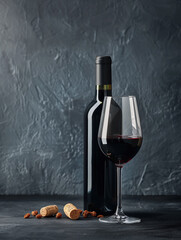 Photo of red , dark wine glass with wine bottle on the table