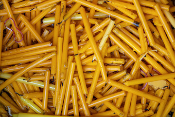 A pile of used candles in a container near an altar in a Buddhist temple