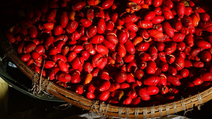 A pile of gnetum gnemon fruit in a bamboo basket exposed to morning sunlight. Focus selected