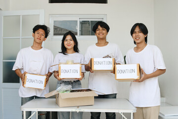 Young volunteers group holding a box of food and drinks for charity event