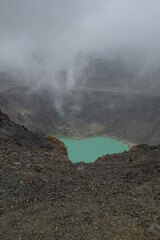 Aerial view of Santa Ana volcano crater with bright turquoise steaming lake water.
