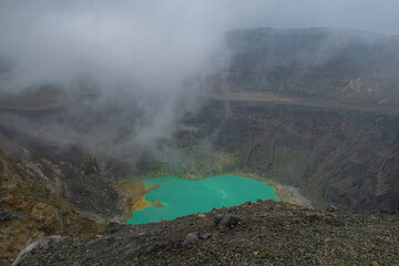 Aerial view of Santa Ana volcano crater with bright turquoise steaming lake water.