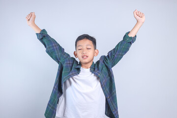 Asian little boy stretching his hand rise up to the air isolated on grey background