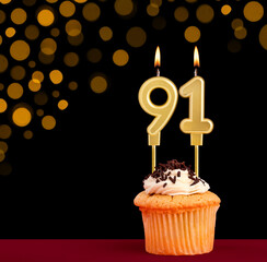 Birthday candle with cupcake - Number 91 on black background with out of focus lights