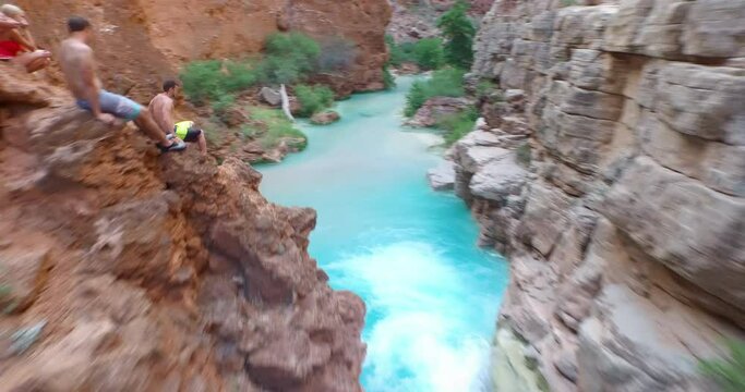High shot over man swimming in blue pool at waterfall base