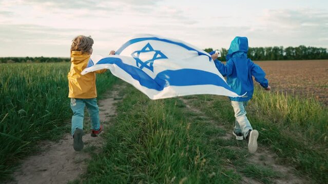Happy israeli jewish little boys runs with Israel national flag. Independence Day. Patriotism. Patriot kids, brothers on open area field, memorial Veterans Day