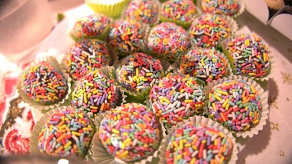 A top view of birthday sweets. A close-up shot of birthday desserts on the table. Distinct granulated and colorful candies. A sweet food plate. Chocolate bits. Sprinkles sweets ready to eat. 