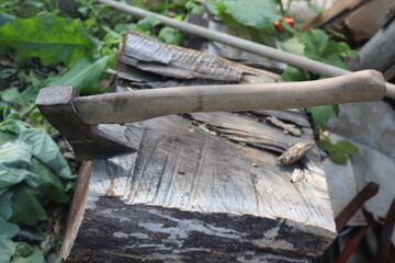 Used Ax hatchet stuck in a wood stump, in courtyard, countryside area