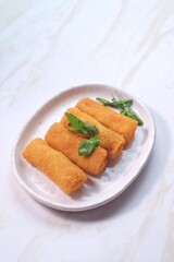 vegetables risoles or risol sayur or risoles sayur stuffed with veggies and enclosed in crepe-like wrappers and rolled into bread crumbs and fried. served on white plate and chili. 
