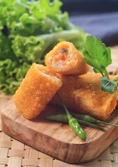 vegetables risoles or risol sayur or risoles sayur stuffed with veggies and enclosed in crepe-like wrappers and rolled into bread crumbs and fried. served on white plate and chili. 
