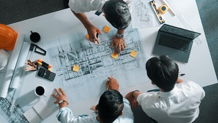 Top down aerial view of interior designer writing at sticky note while planning design with engineer team. Group of diverse architect and skilled manager looking building construction. Alimentation.
