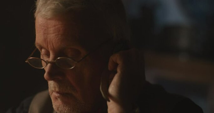 Old watchmaker working alone at night.
