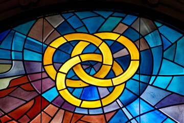 Modern stained glass window symbolically representing the divine trinity: Father, Son and Holy...