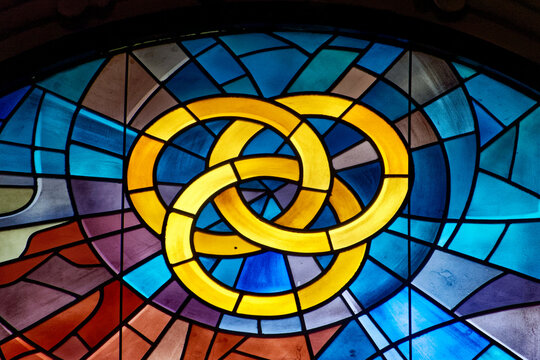 Modern stained glass window symbolically representing the divine trinity: Father, Son and Holy Spirit. Vitrail moderne repr&eacute;sentant symboliquement la trinit&eacute; divine, P&egrave;re, fils et Esprit Saint. Italie