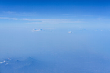 view of the bright blue sky and mountains on the island of Java from the plane window, blue sky with clouds, See Through Plane Window With Blue Sky And Clouds Outside, travel trip over Java island