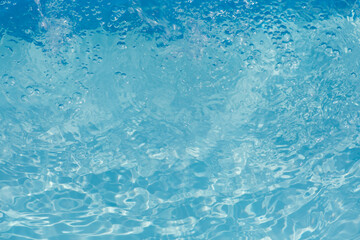 Blue water with ripples on the surface. Defocus blurred transparent blue colored clear calm water surface texture with splashes and bubbles. Water waves with shining pattern texture background.