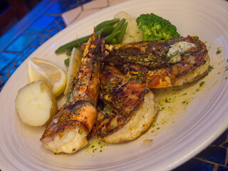 Grilled Kuruma Giant Tiger Prawns on white plate with boiled potato and vegetables close up, dining in famous Stanley village in Hong Kong