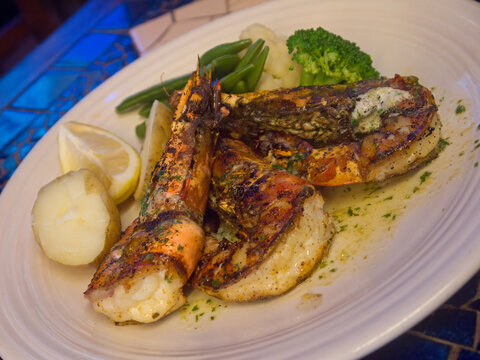 Grilled Kuruma Giant Tiger Prawns on white plate with boiled potato and vegetables close up, dining in famous Stanley village in Hong Kong
