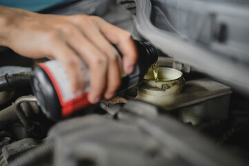 Auto mechanic adding brake fluid to the reservoirs.	
