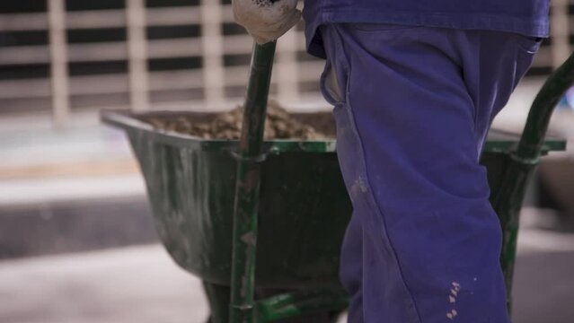 trabajador lleva una carreta llena de cemento o tierra, y la deposita.