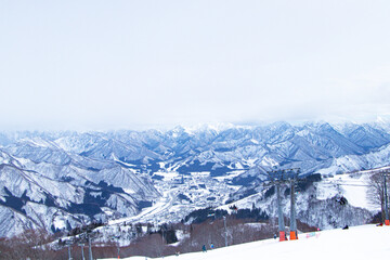 Village landscape in the middle of a snowy valley with lift or ropeway to go skiing snow. Mountain peak white snow in winter at Japan. Great place for winter sports. Suitable for  travel tourists.