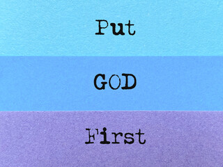 Put God first text on multicoloured paper background. Stock photo.